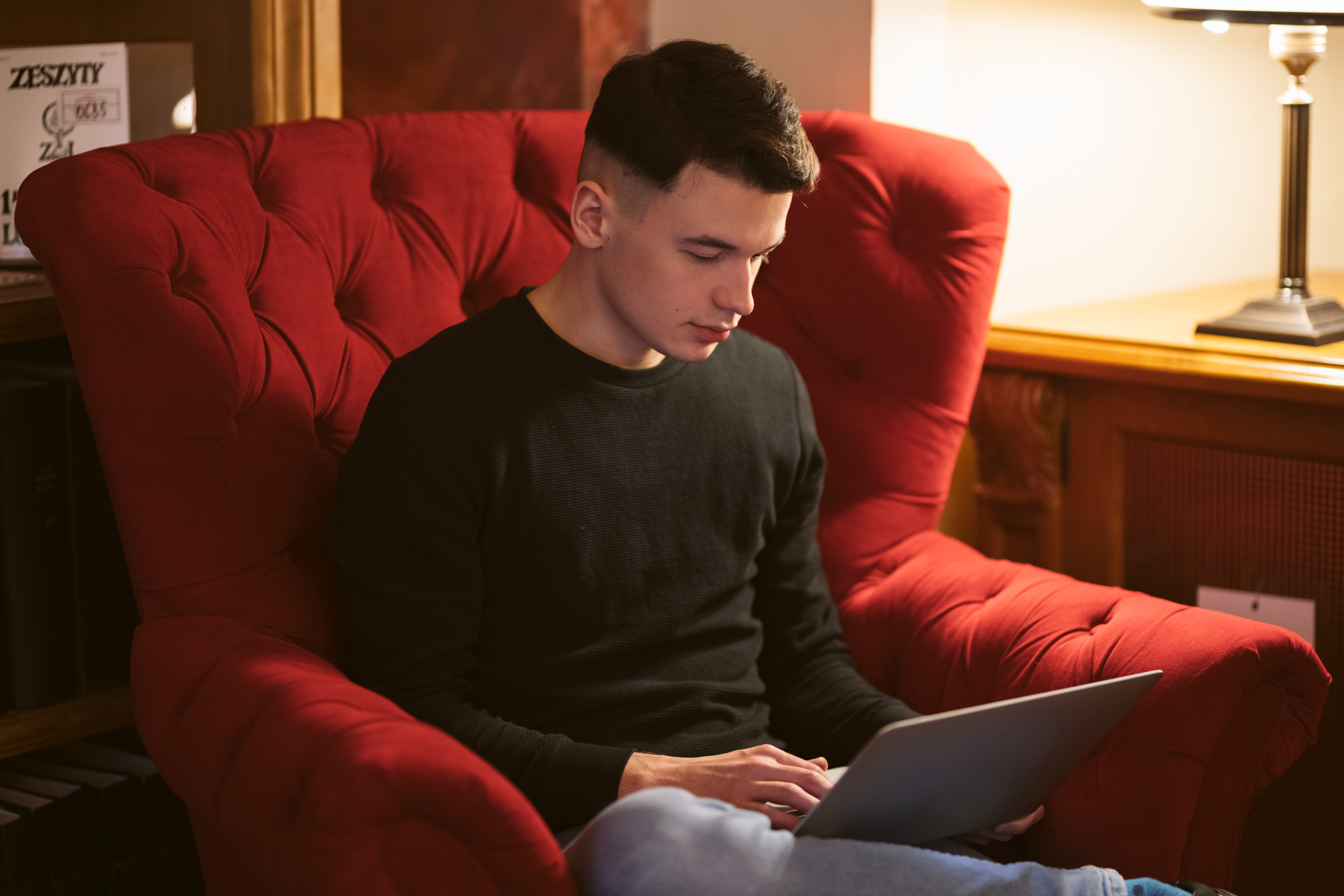 Osoba siedząca w fotelu z laptopem na kolanach