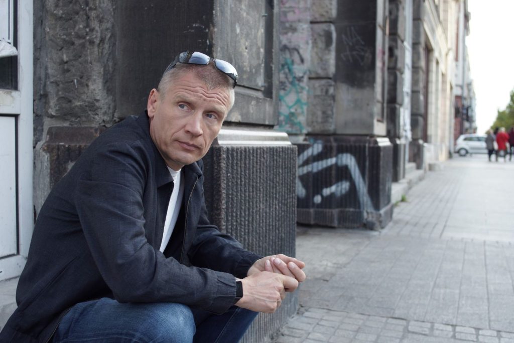 Tomasz Patora siedzący na schodach na chodniku